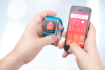 Die linke Hand hält eine Smartwatch, die rechte Hand hält eine Smartphone. Es findet eine Datenübertragung zwischen den beiden Geräten statt.